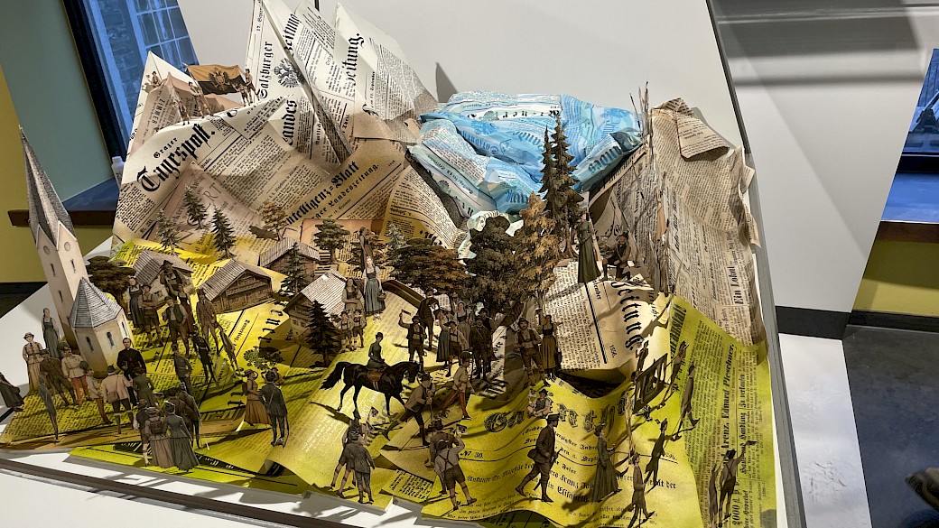 Die aus filigranen Papierschnitten angefertigte Szenografie zeigt die verschiedenen Episoden der Reise des Kaiserpaares von Heiligenblut Richtung Großglockner.